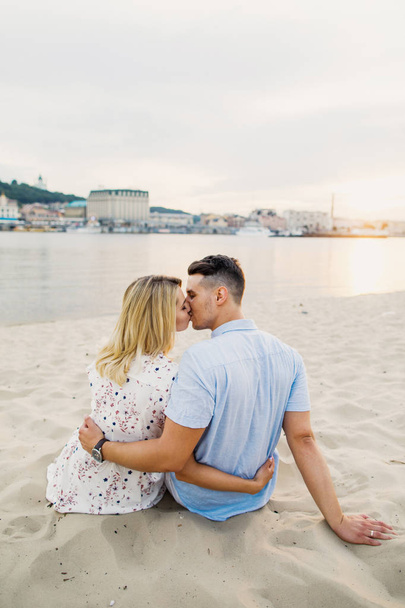 couple posing sitting on sand and kissing - Photo, image