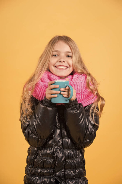 Child hold mug in black jacket and pink scarf - Фото, изображение