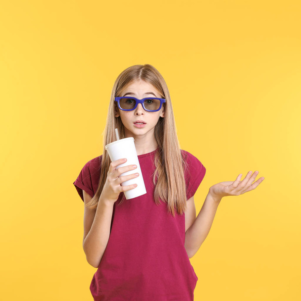 Emotional teenage girl with 3D glasses and beverage during cinema show on color background - Fotoğraf, Görsel