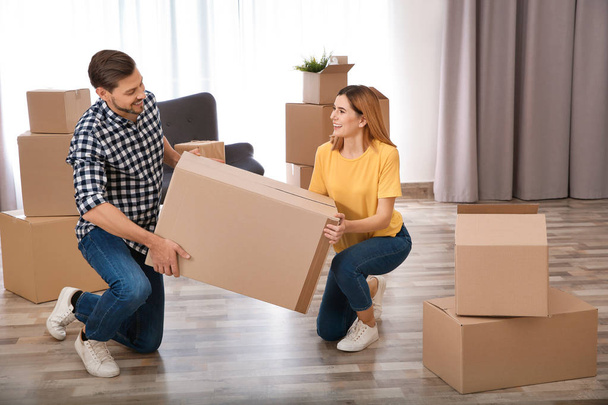 Couple with moving box in their new house - Фото, изображение