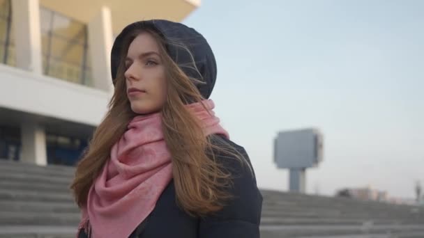 Woman in a coat with a pink scarf goes and looks at his feet - Záběry, video