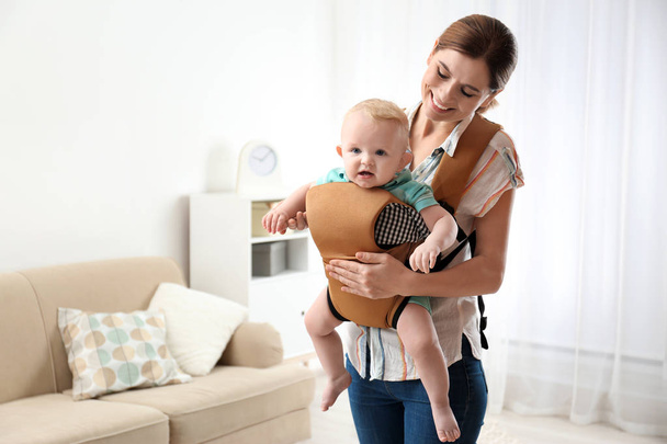 Woman with her son in baby carrier at home. Space for text - Fotoğraf, Görsel