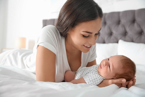 Young woman with her newborn baby on bed - Photo, image