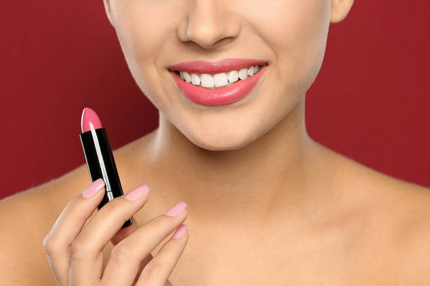 Young woman applying lipstick on color background, closeup - Foto, imagen