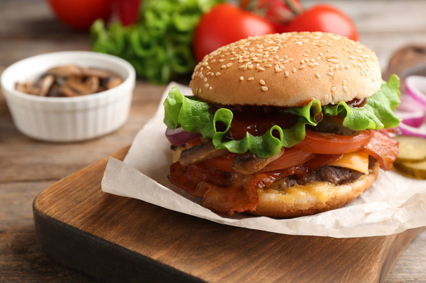Tasty burger with bacon on wooden board, closeup - Φωτογραφία, εικόνα