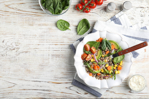 Healthy quinoa salad with vegetables in plate served on table, top view. Space for text - Фото, изображение