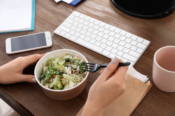 Office employee having salad for lunch at workplace, closeup. Food delivery - Fotoğraf, Görsel