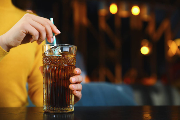 Woman with glass of refreshing cola at table indoors, closeup. Space for text - Foto, Imagen
