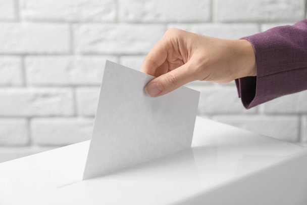 Woman putting her vote into ballot box against brick wall, closeup - Photo, Image
