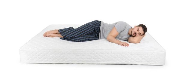 Young man lying on mattress against white background - Фото, зображення