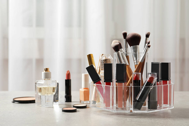 Lipstick holder with different makeup products on table indoors. Space for text - 写真・画像