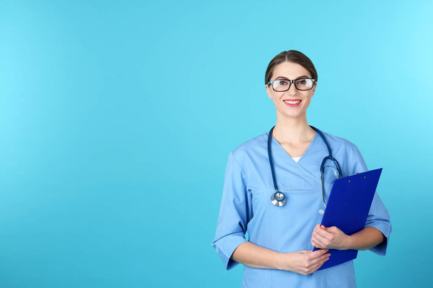 Young medical student with clipboard on color background. Space for text - Foto, Bild
