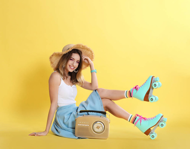 Jonge vrouw met rolschaatsen en retro radio op de achtergrond kleur - Foto, afbeelding