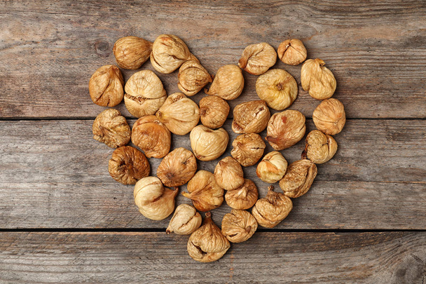 Heart made of figs on wooden background, top view. Dried fruit as healthy food - Photo, image