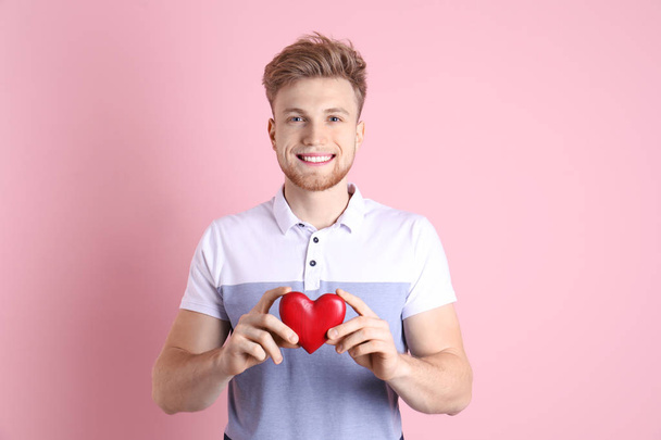 Portrait of young man with decorative heart on color background - Foto, imagen