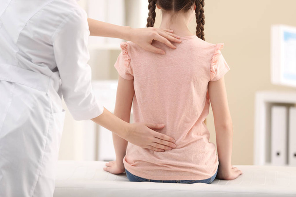 Chiropractor examining child with back pain in clinic, closeup - Foto, afbeelding