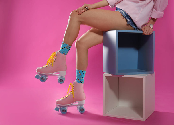 Young woman with retro roller skates on color background, closeup - 写真・画像