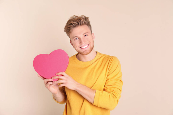Portrait of young man with decorative heart on color background - Foto, Imagen