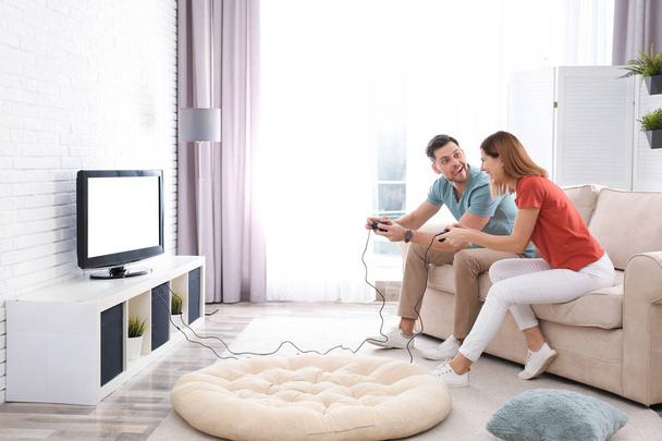 Happy couple playing video games in living room - Fotoğraf, Görsel