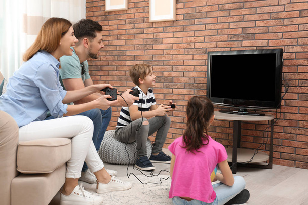 Happy family playing video games in living room - Foto, afbeelding