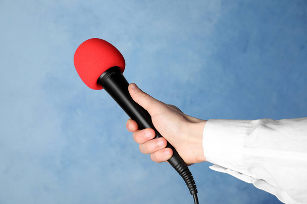 Woman holding microphone on color background, closeup - Фото, изображение