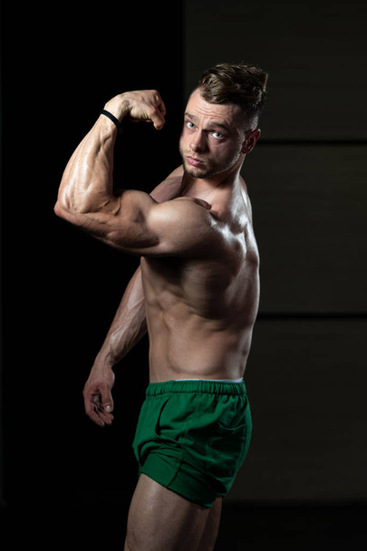 Young Man Standing Strong In The Gym And Flexing Muscles - Muscular Athletic Bodybuilder Fitness Model Posing After Exercises - Fotoğraf, Görsel