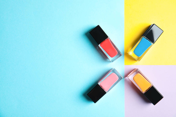 Bottles of nail polish on color background, top view with space for text - Фото, зображення