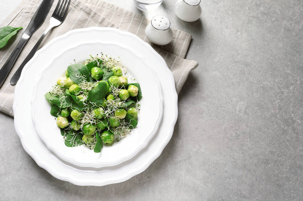 Plate of delicious salad with Brussels sprouts on grey table, top view. Space for text - Фото, изображение