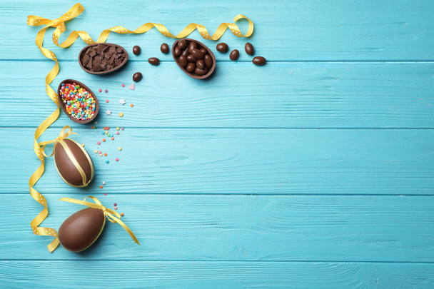 Frame made of chocolate Easter eggs on color wooden background, top view with space for text - Foto, afbeelding
