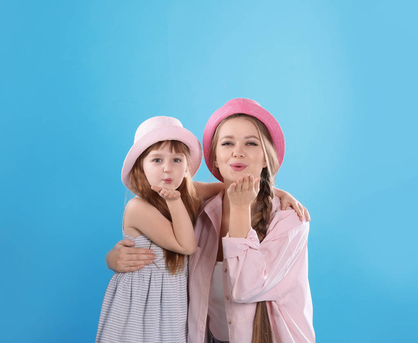 Happy woman and daughter in stylish clothes on color background - 写真・画像