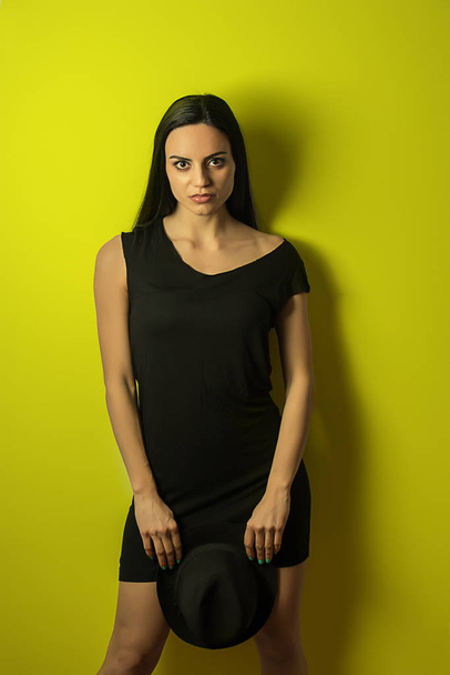Girl in black with a hat on a yellow background - Fotografie, Obrázek