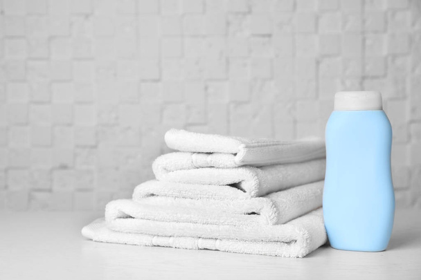 Bottle with shampoo and soft bath towels on table - Photo, image