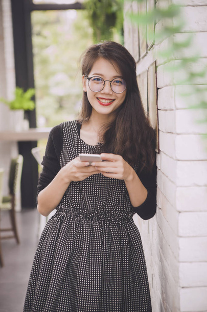 gyönyörű ázsiai fiatalabb nő toothy mosolygó arc smartphone boldogság érzés a kezében - Fotó, kép