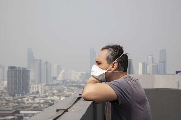 ενήλικα άνδρα που φοράει προστατευτική μάσκα στη στέγη με αστικό τοπίο - Φωτογραφία, εικόνα