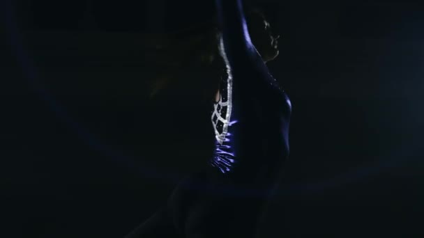 Het meisje voert een rotatie in de artistieke gymnastiek op een donkere achtergrond in de rook in slowmotion closeup - Video