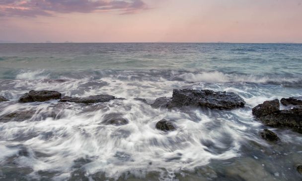 Movimiento de larga exposición ola paisaje marino estrellándose roca en el fondo del paisaje puesta de sol
 - Foto, Imagen