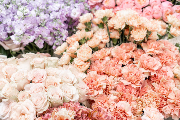 Floral carpet, flower texture, shop concept. Beautiful fresh blossoming flowers roses, spray roses, lilac gillyflower and carnation. Blossom of pastel color in vases and pails. Top view. - 写真・画像
