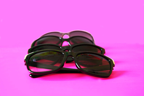 Lunettes de soleil sur fond rose pastel. Lunettes avec montures noires. Accessoires de mode de protection UV des yeux
. - Photo, image