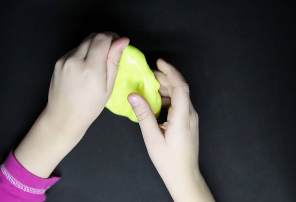 Chica jugando con limo amarillo en sus manos
. - Foto, imagen