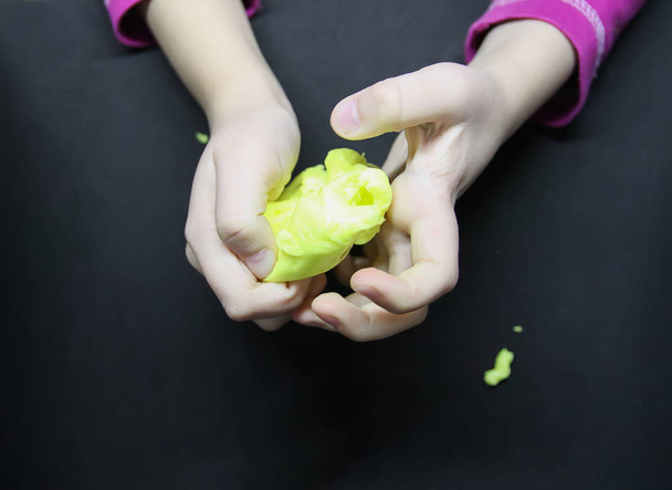 Girl playing with yellow slime in her hands. - Foto, imagen