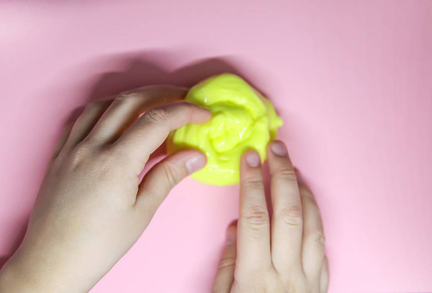 Girl playing with yellow slime in her hands. - 写真・画像