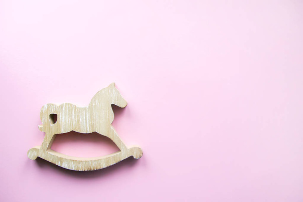 Schaukelpferd. Dekorative Figur aus Holz auf zartem rosa Pastellhintergrund. - Foto, Bild
