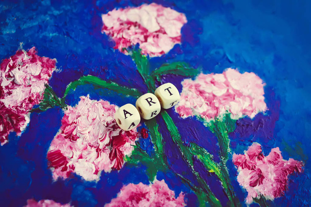Palabra de arte de cuentas de madera en la imagen. Flores de clavel dibujadas a mano sobre fondo azul brillante. Imagen hecha por aceite sobre cartón. - Foto, Imagen