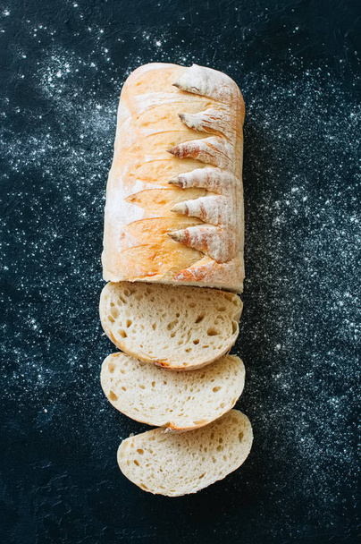 Homemade white sourdough bread with flour on a black background. Top view. - Fotografie, Obrázek