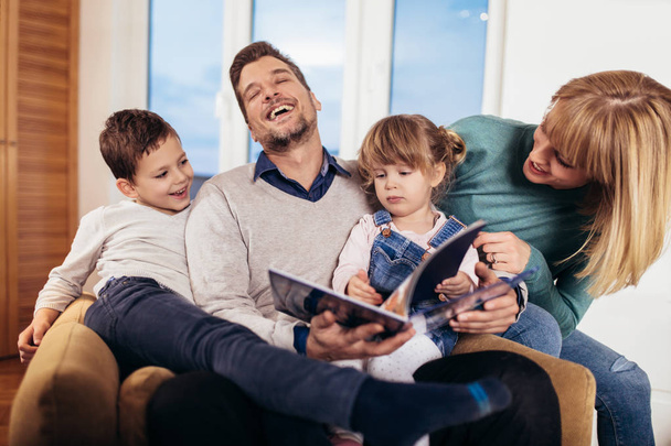 Happy family reading book at home - Photo, Image