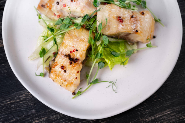 Sült fehér halszeletek, zöld borsó hajtások fehér tányérra fűszerek - Fotó, kép