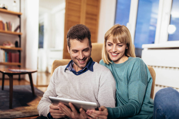Cheerful couple using digital tablet at home - Fotoğraf, Görsel