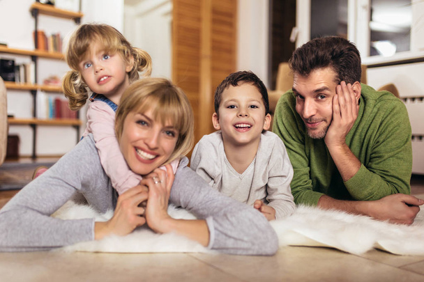 Happy family having fun on floor of in living room at home, laughing, selective focus. - Foto, imagen