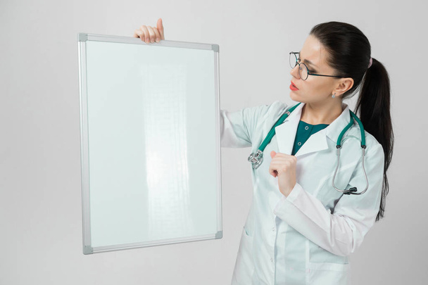 Portrait of woman wearing glasses in white robe with magnetic Board in hands isolated on white background - Photo, Image