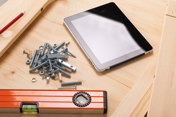 строительный инструмент и цифровая табличка лежат на светлом деревянном столе
 - Фото, изображение